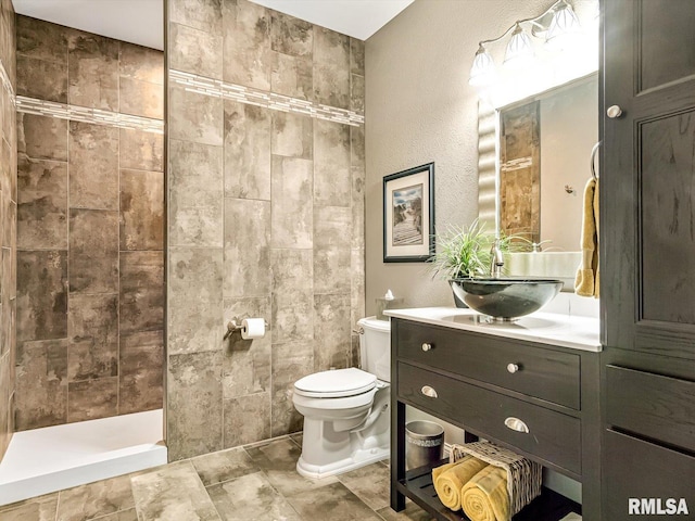 bathroom featuring tiled shower, vanity, and toilet