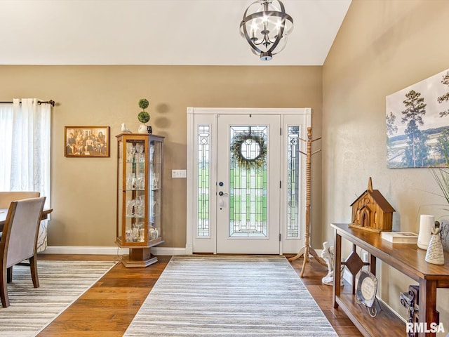 foyer with wood-type flooring, vaulted ceiling, and a chandelier