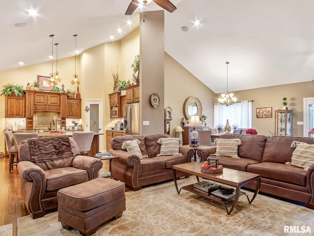 living room featuring ceiling fan with notable chandelier, light wood-type flooring, high vaulted ceiling, and sink