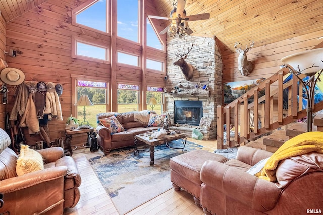 living room featuring a stone fireplace, hardwood / wood-style flooring, lofted ceiling, and wood walls