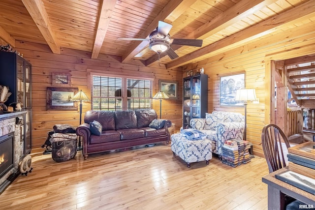 living area with a stone fireplace, beamed ceiling, light wood-style floors, and wood ceiling