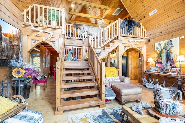 staircase with wooden walls, wood finished floors, high vaulted ceiling, arched walkways, and wooden ceiling