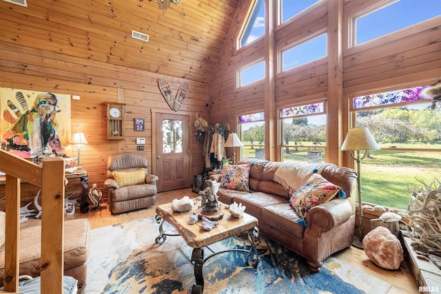 living area with plenty of natural light, wood finished floors, wood walls, and high vaulted ceiling