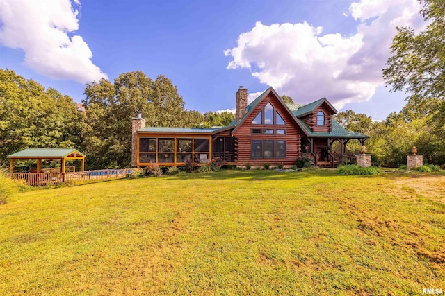 back of property featuring a gazebo, log exterior, a chimney, and a yard