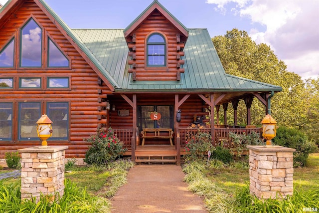 log-style house with metal roof, covered porch, and log exterior