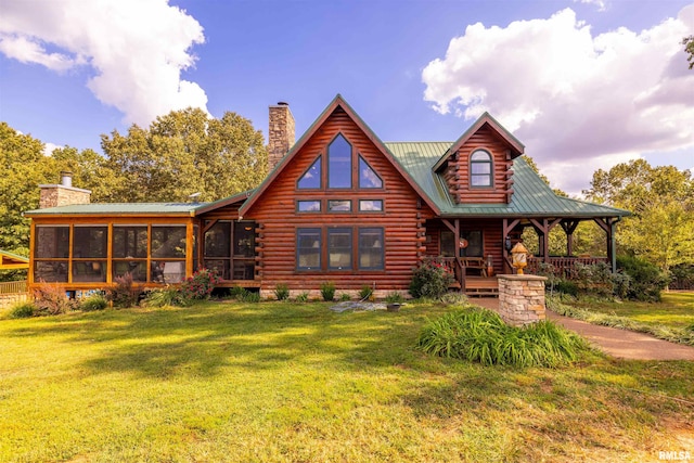 back of property with log siding, a yard, a sunroom, and a chimney