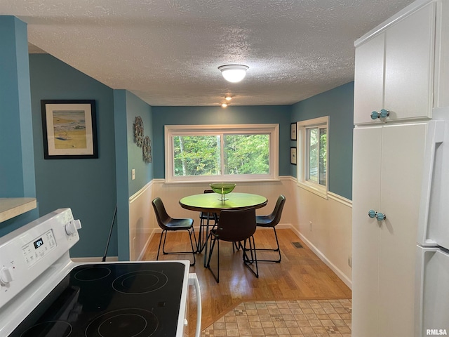 dining room with light wood-type flooring and a textured ceiling