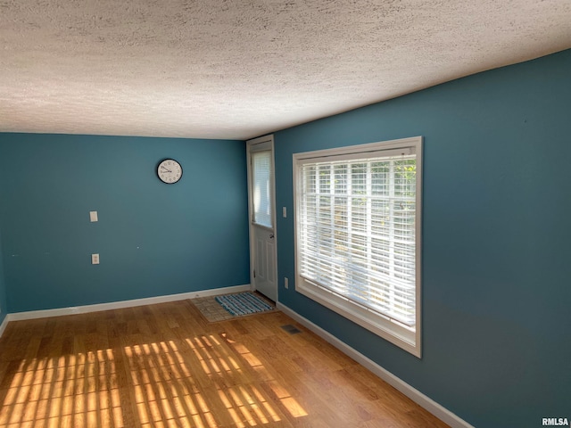 unfurnished room with a textured ceiling and hardwood / wood-style flooring