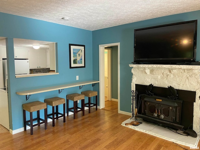 living room featuring light hardwood / wood-style floors, a textured ceiling, and a fireplace