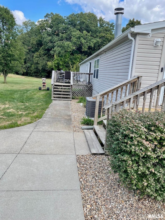 view of property exterior featuring a lawn, central AC, and a wooden deck