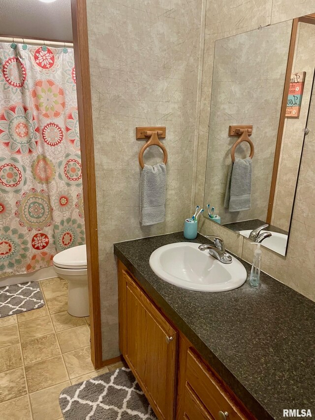 bathroom featuring tile patterned flooring, curtained shower, vanity, and toilet