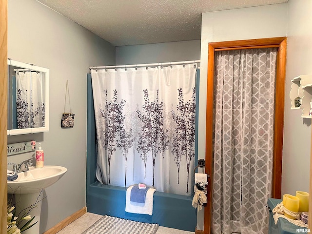 bathroom featuring a textured ceiling, shower / tub combo, and sink