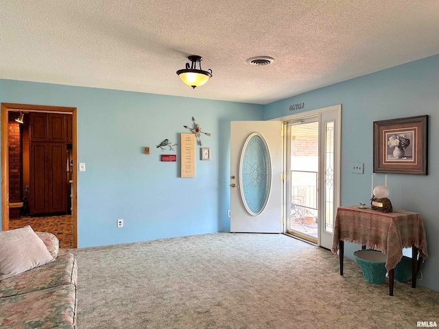 carpeted foyer featuring a textured ceiling