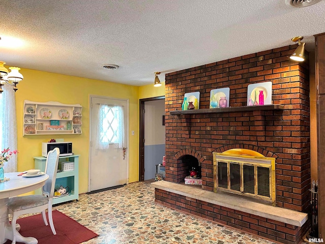 living room with a textured ceiling and a brick fireplace