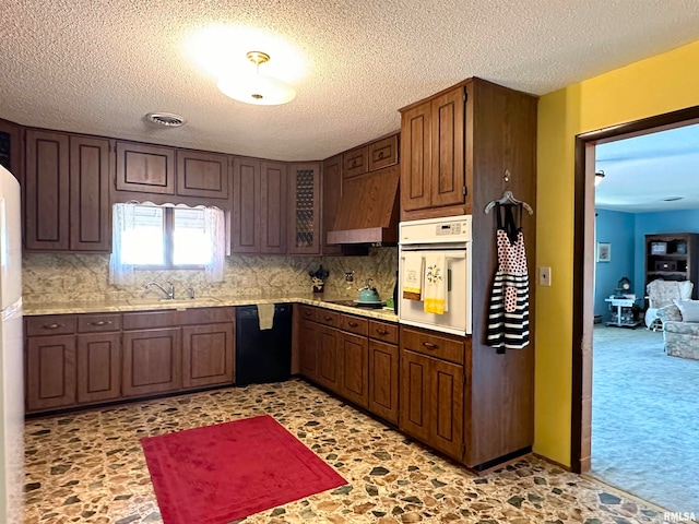 kitchen featuring tasteful backsplash, a textured ceiling, black appliances, custom exhaust hood, and sink