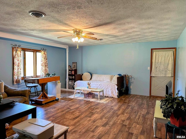 living room with ceiling fan, a textured ceiling, and dark wood-type flooring