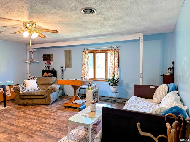 living room featuring ceiling fan, a baseboard radiator, hardwood / wood-style floors, and a textured ceiling