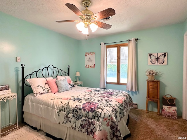 bedroom with ceiling fan, light colored carpet, and a textured ceiling