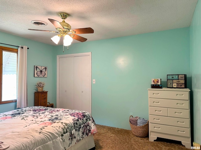 bedroom featuring a closet, ceiling fan, carpet floors, and a textured ceiling