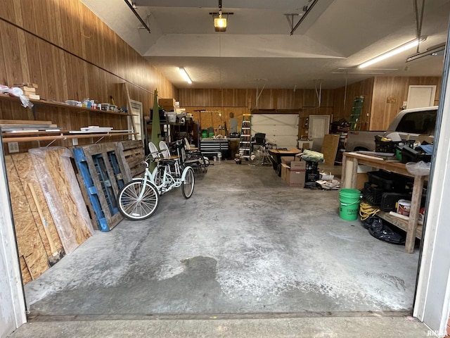 garage featuring wooden walls, a garage door opener, and a workshop area