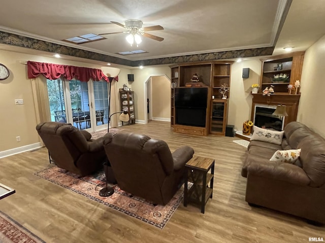 living room featuring light wood-style floors, a fireplace, arched walkways, a ceiling fan, and baseboards