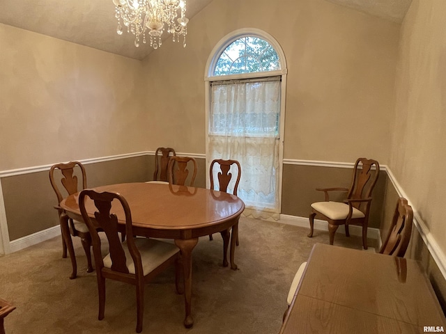 carpeted dining space featuring baseboards, an inviting chandelier, and lofted ceiling