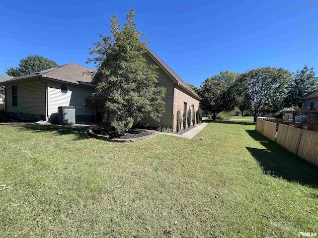 rear view of house with cooling unit, a yard, and fence