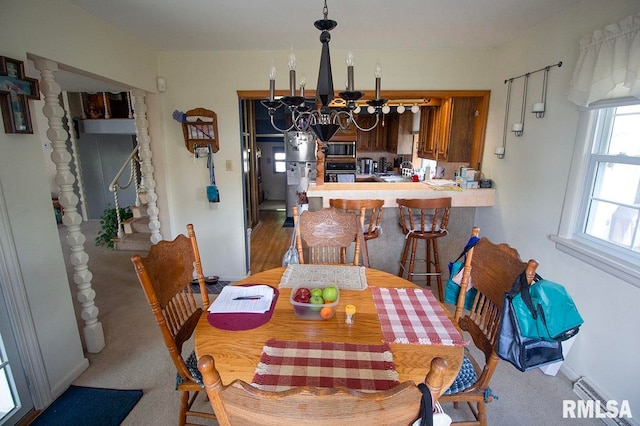 carpeted dining area with an inviting chandelier and a baseboard heating unit