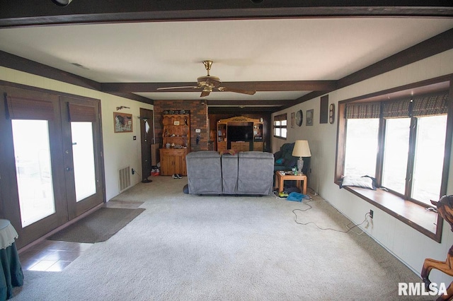 carpeted living room with ceiling fan and beamed ceiling