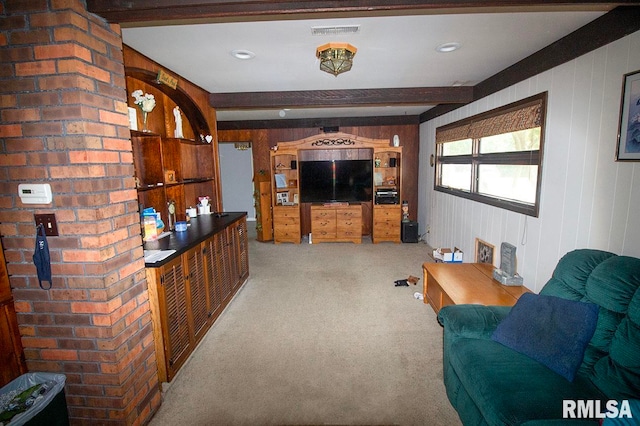 carpeted living room with beam ceiling and wood walls