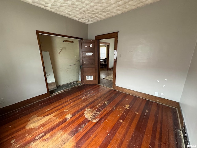 spare room featuring a textured ceiling and dark hardwood / wood-style floors