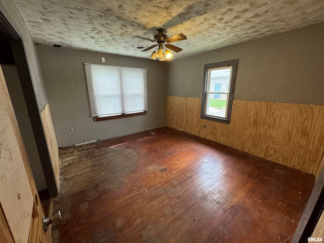 empty room with wood walls, ceiling fan, and dark hardwood / wood-style floors