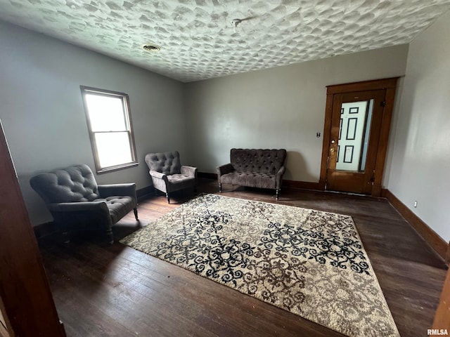 living area with a textured ceiling and dark hardwood / wood-style floors