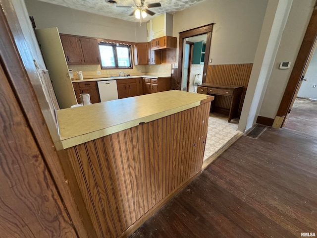 kitchen with kitchen peninsula, dishwasher, a textured ceiling, ceiling fan, and hardwood / wood-style flooring