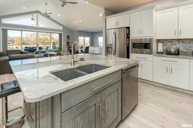 kitchen with white cabinetry, light stone countertops, a spacious island, decorative backsplash, and appliances with stainless steel finishes