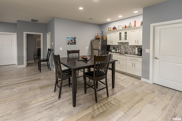 dining space with light hardwood / wood-style floors and wet bar