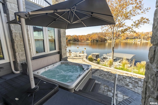 view of patio / terrace featuring a water view and an outdoor hot tub