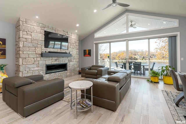 living room with high vaulted ceiling, light hardwood / wood-style floors, a stone fireplace, and ceiling fan