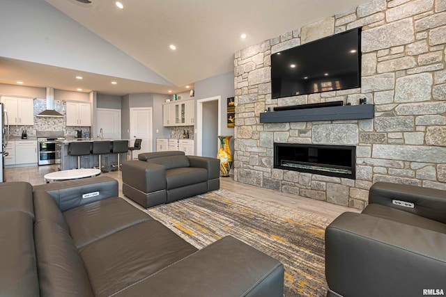 living room featuring a fireplace, hardwood / wood-style floors, high vaulted ceiling, and sink