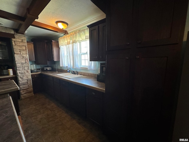 kitchen featuring a textured ceiling, dark brown cabinetry, and sink