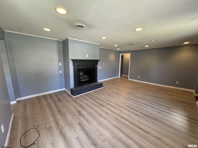 unfurnished living room with recessed lighting, wood finished floors, baseboards, and a fireplace with raised hearth