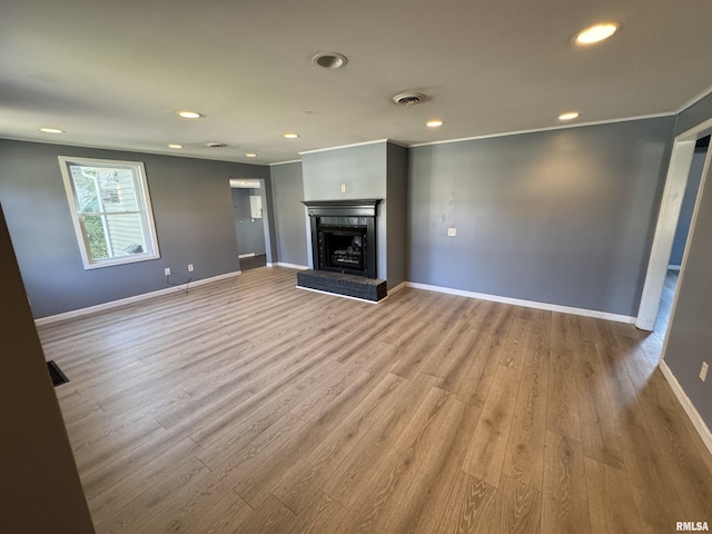 unfurnished living room with wood finished floors, a brick fireplace, baseboards, recessed lighting, and ornamental molding