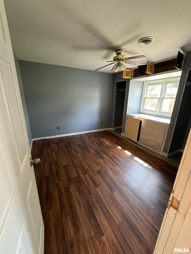 unfurnished bedroom with dark wood-style floors, a ceiling fan, and baseboards