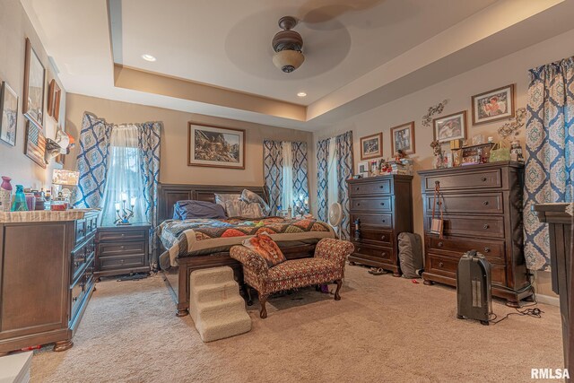 carpeted bedroom with a tray ceiling and ceiling fan