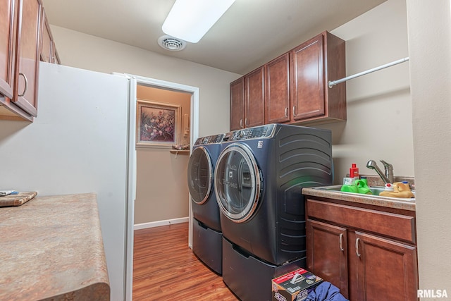 clothes washing area featuring sink, independent washer and dryer, light wood-type flooring, and cabinets