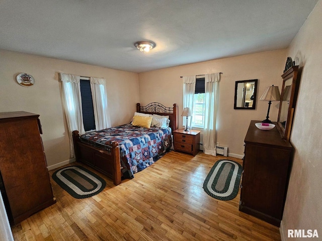 bedroom with light hardwood / wood-style flooring and a baseboard heating unit