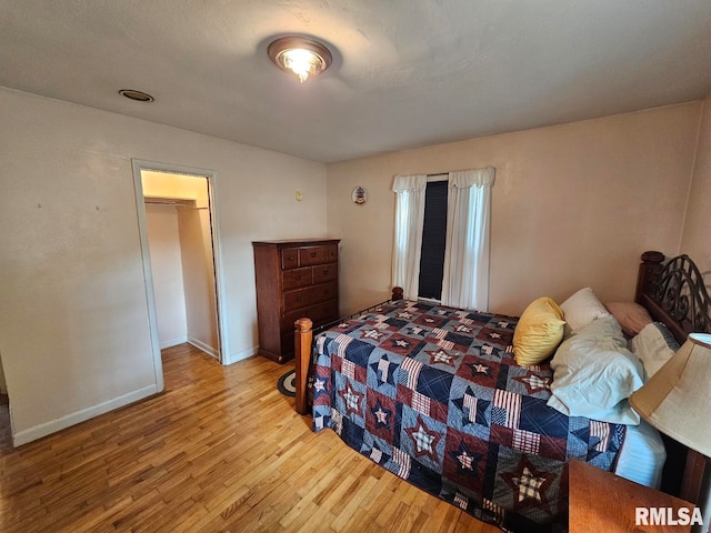 bedroom with light hardwood / wood-style flooring, a closet, and a walk in closet