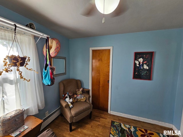 sitting room featuring wood-type flooring, ceiling fan, and a baseboard radiator