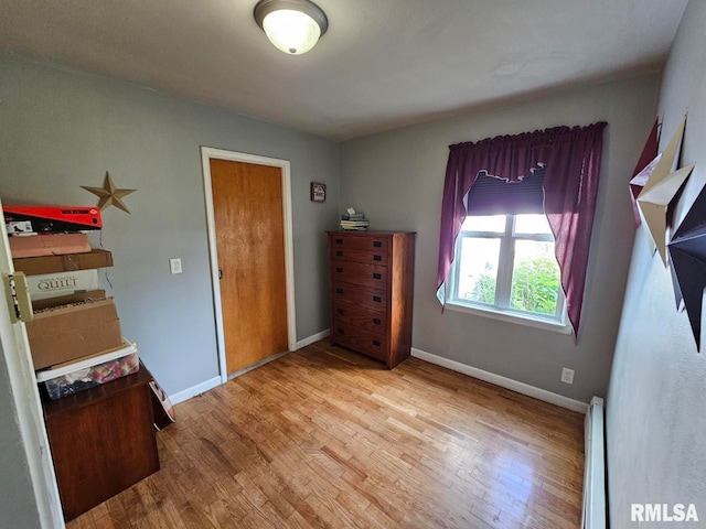 bedroom with baseboard heating and light hardwood / wood-style flooring