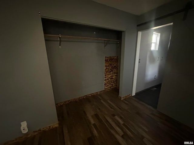 unfurnished bedroom with a closet and dark wood-type flooring